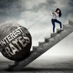 Young businesswoman is pulling big stone with text of interest rates while climbing on the stair